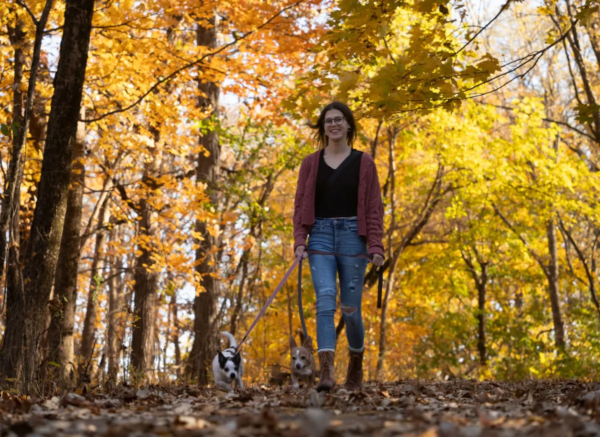 Portrait de l’éducatrice en forêt à l’automne, son chien à ses côtés