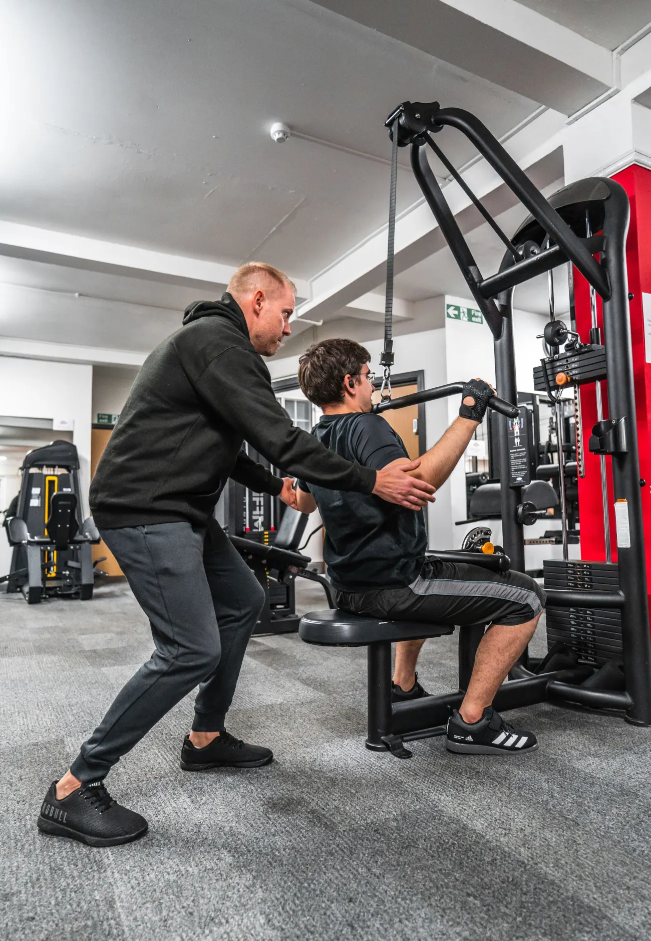 Coach qui guide un client sur un mouvement en salle