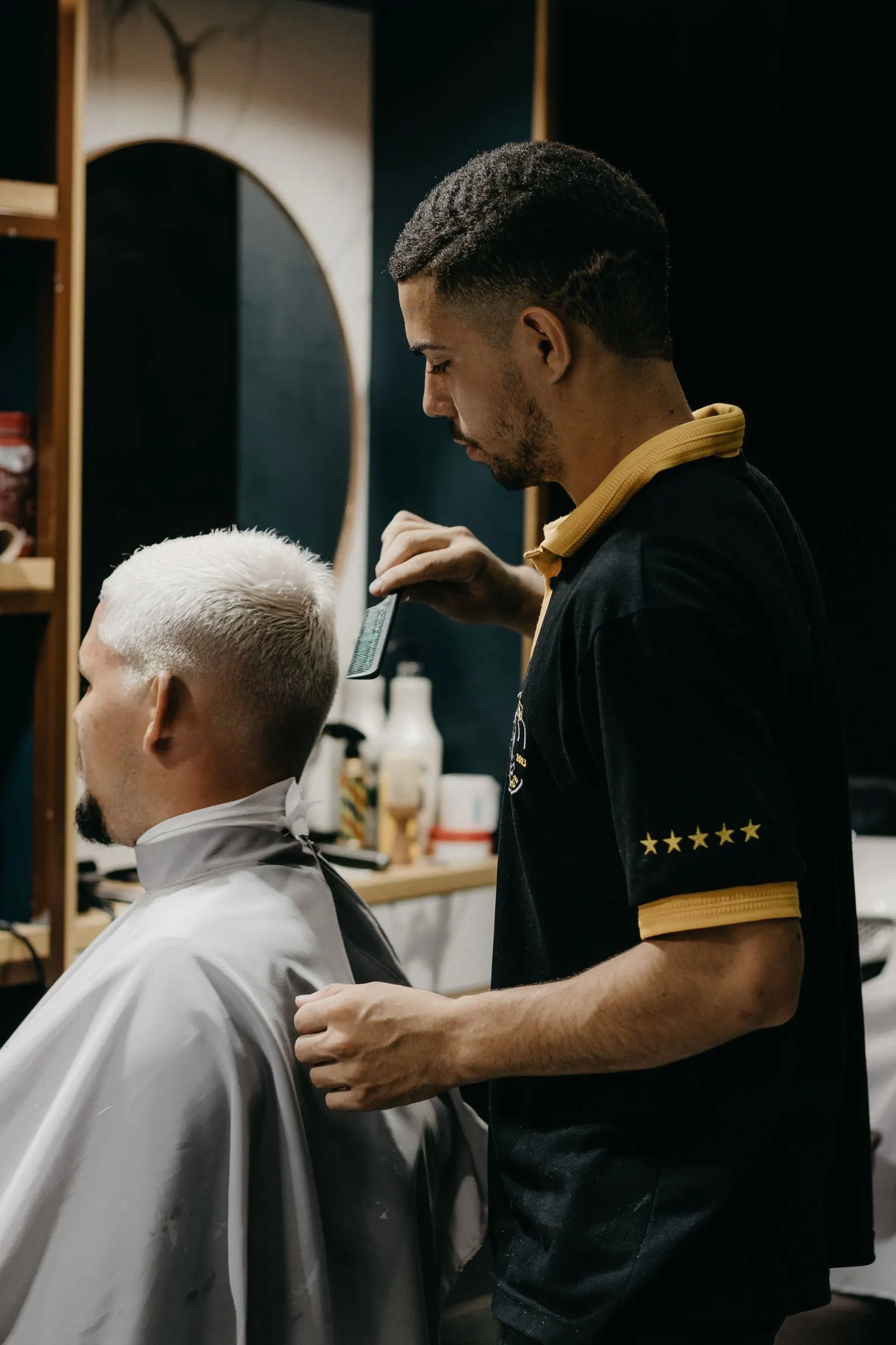 Le barber réalise un dégradé à la tondeuse sur un client aux cheveux décolorés, dans le shop