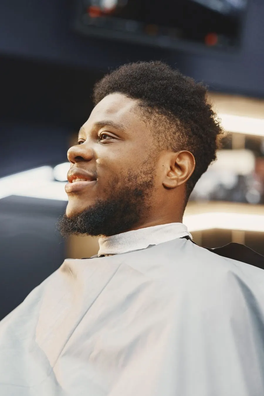 Taper fade et barbe, client souriant en cape