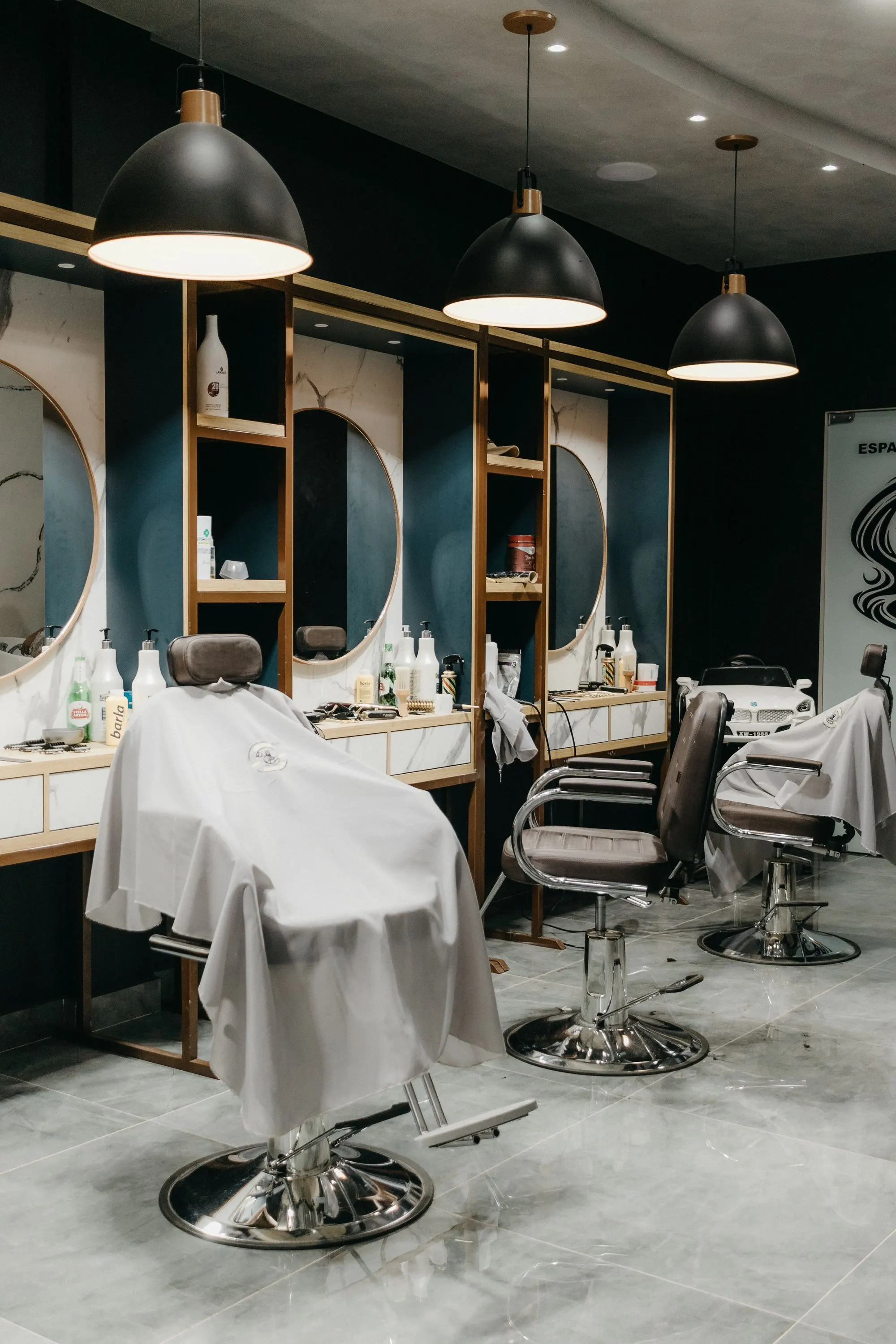 L’intérieur du shop : fauteuils de barbier alignés, miroirs ronds et suspensions noires