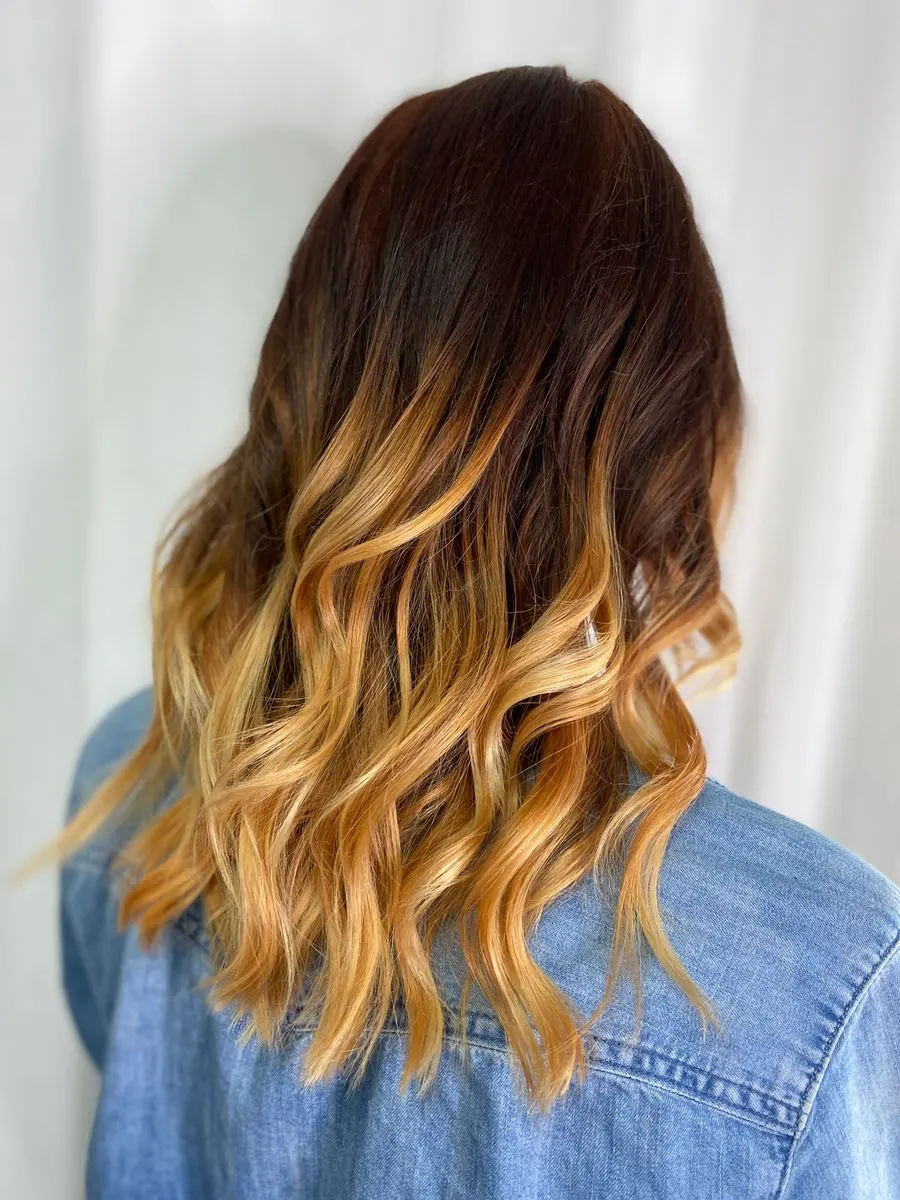 Longueurs ondulées éclaircies par un balayage doré, vue de dos
