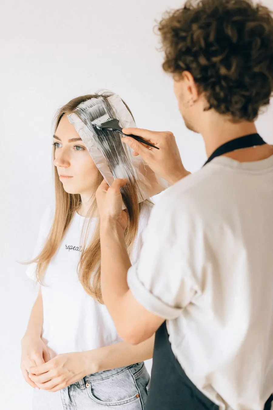 Coloriste posant une couleur au pinceau sur une mèche de cheveux longs
