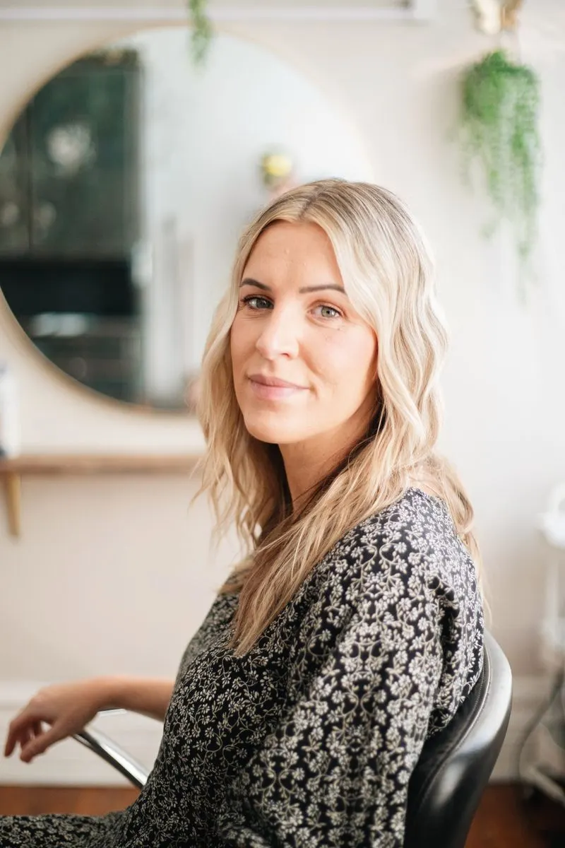 Portrait d’Emma, coiffeuse aux cheveux blonds ondulés, dans le salon