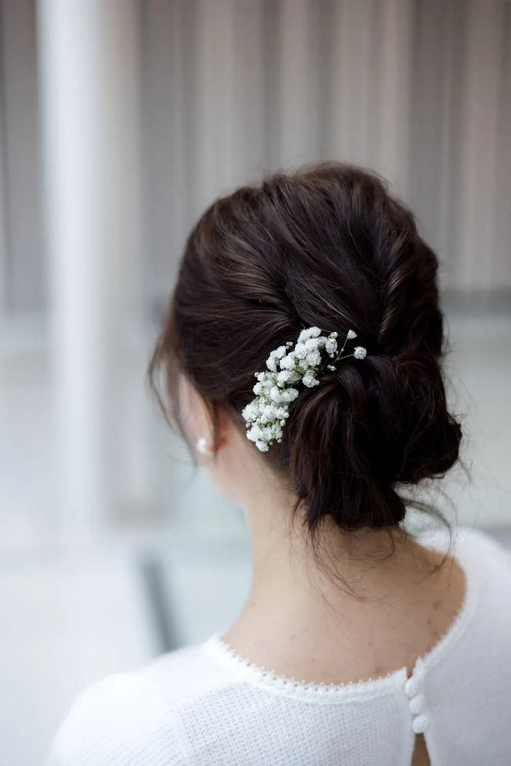 Chignon bas brun piqué de petites fleurs blanches, vue de dos