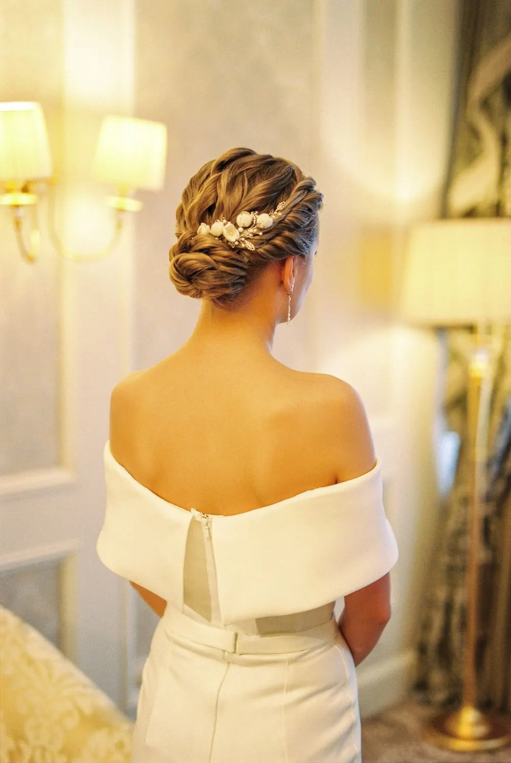 Chignon tressé orné de perles, lumière dorée d’une salle de réception