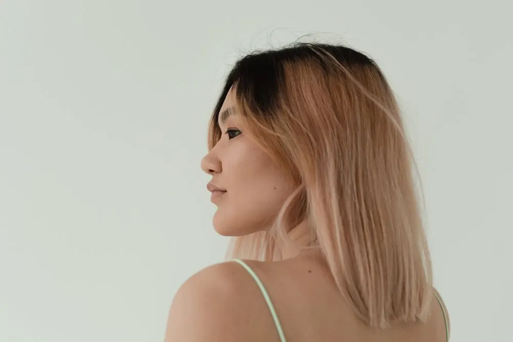Profil d’une femme aux cheveux dégradés du brun au rose poudré