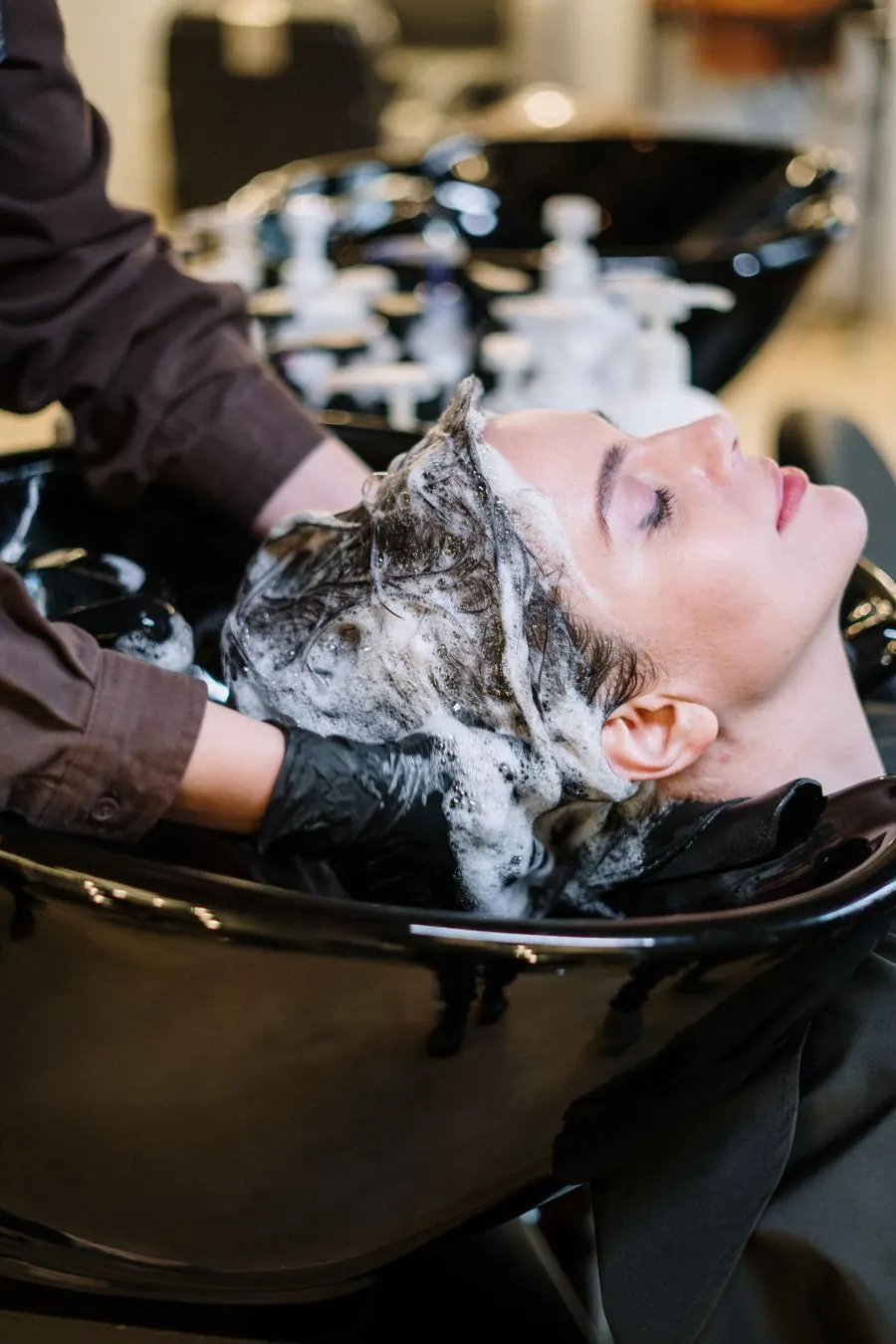 Shampoing soin au bac, la cliente allongée, les yeux fermés