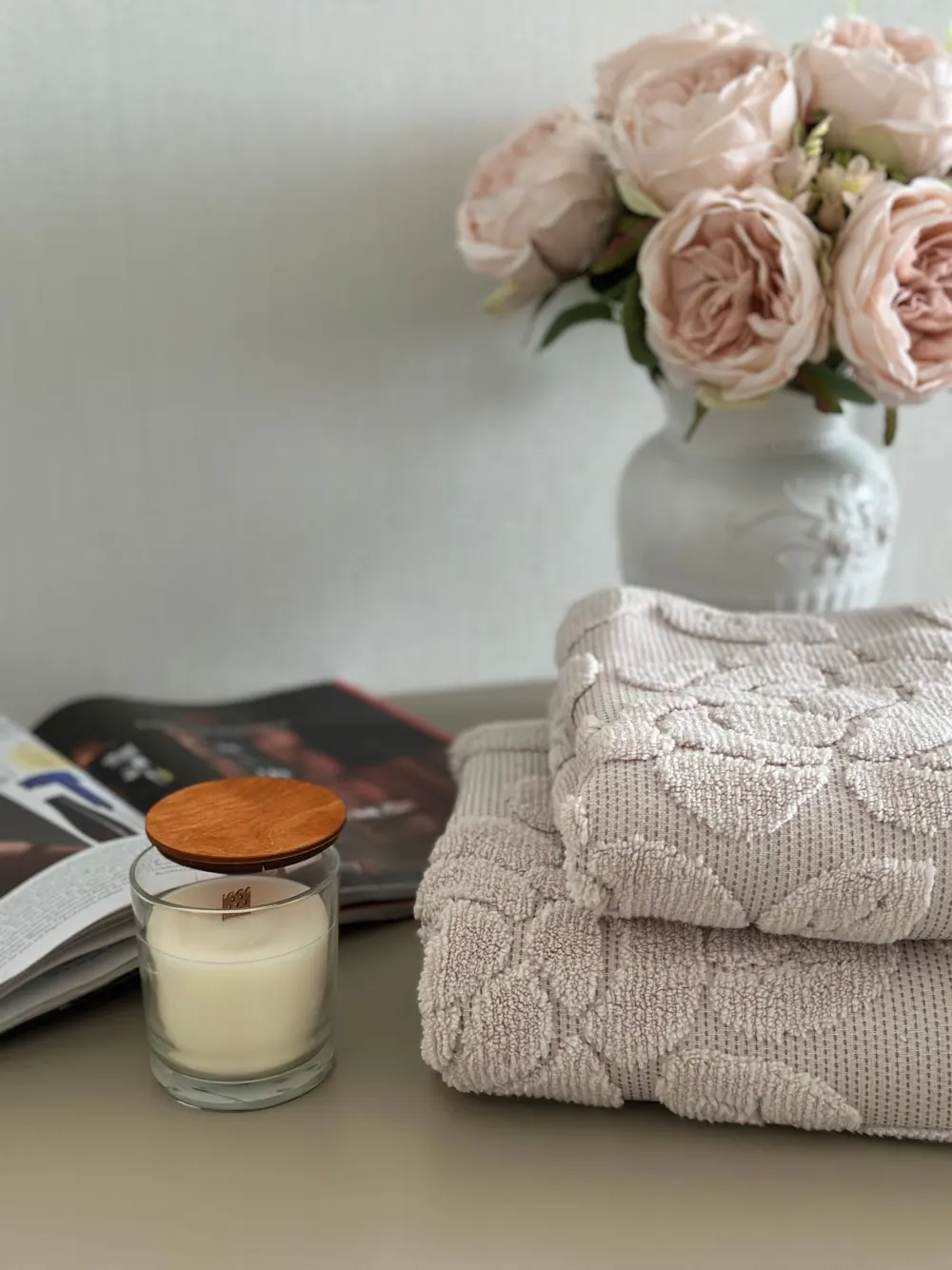 Serviettes pliées, bougie et roses claires