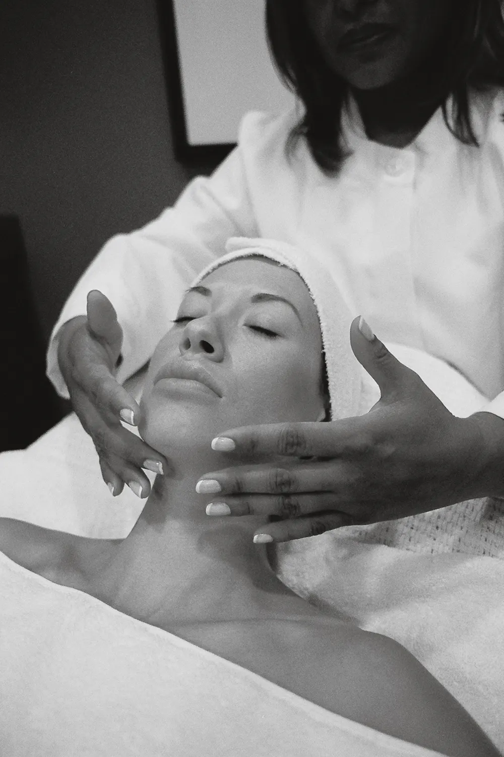 Soin du visage en noir et blanc, mains sur le front de la cliente