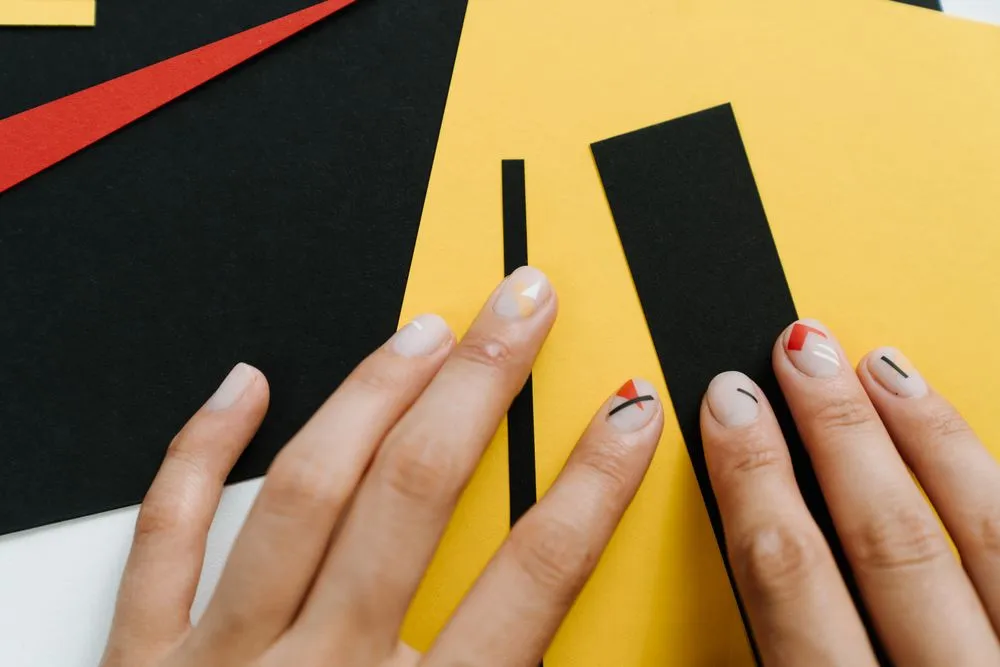 Lignes graphiques noires et orange sur ongles nude