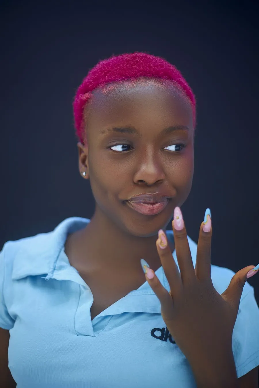 Portrait d’Inès, souriante, qui montre ses ongles