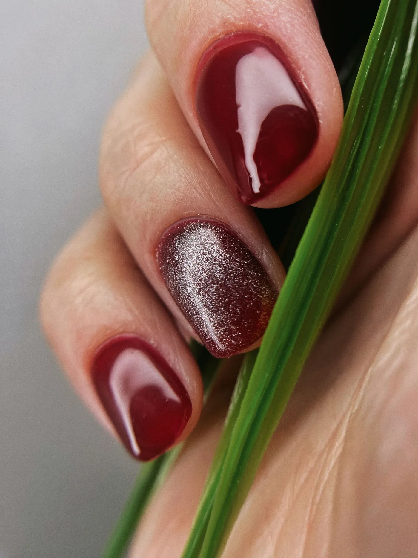 Ongles bordeaux laqués et effet œil de chat, en macro