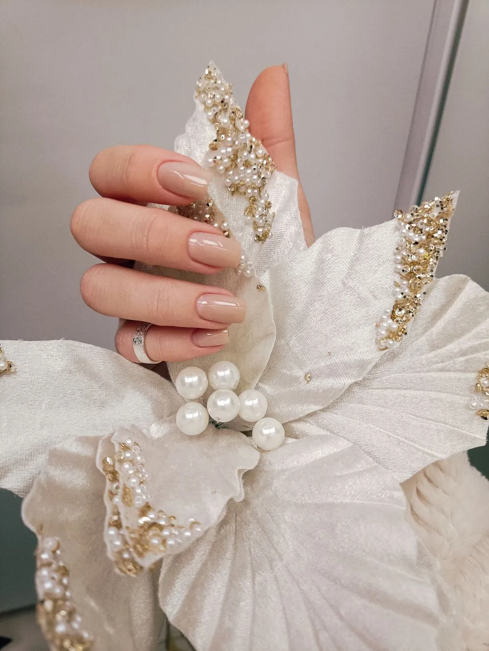 Ongles nude ornés de perles et d’une fleur en relief