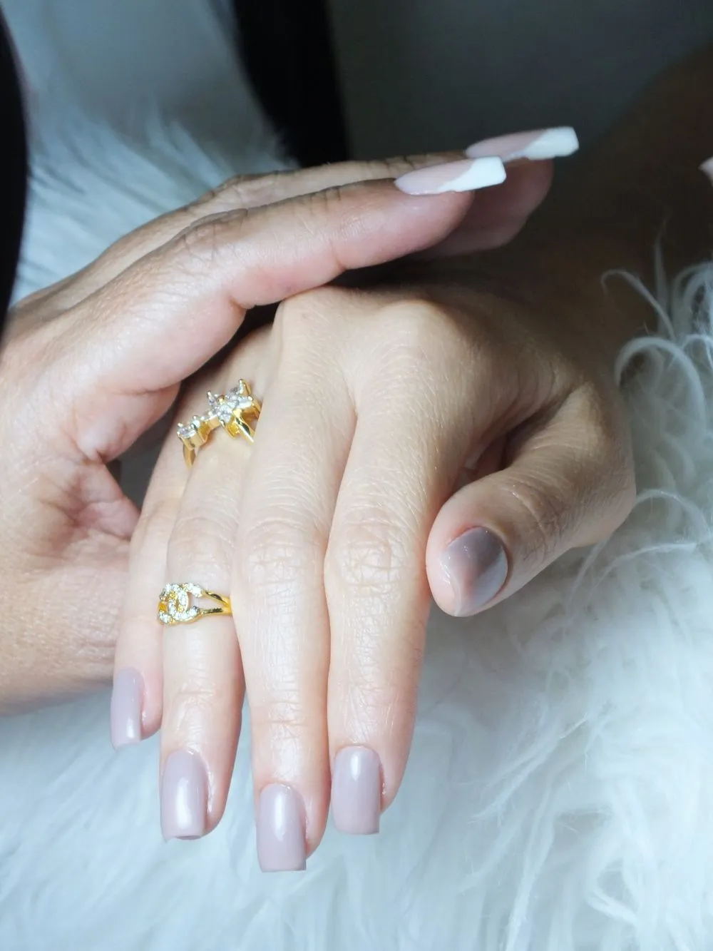 Ongles carrés nude sur une fourrure blanche, bagues dorées