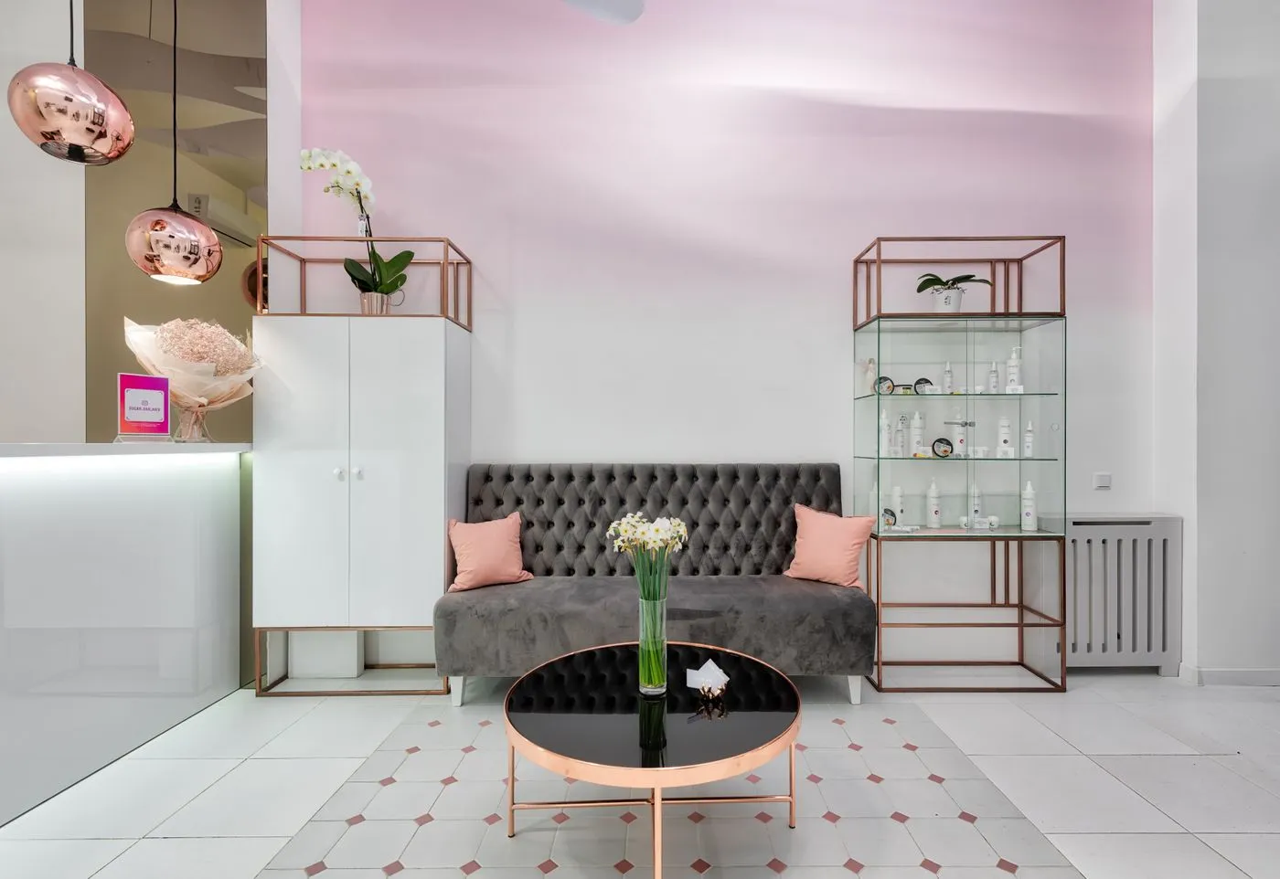 Le coin d’accueil du studio : canapé capitonné, table ronde en verre et fleurs fraîches
