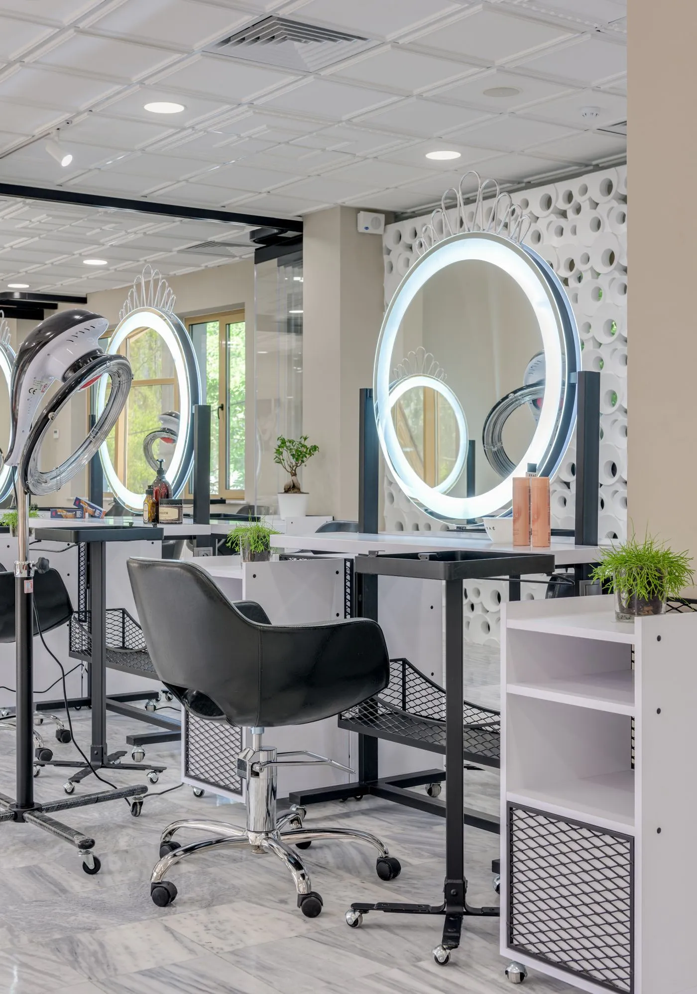 Le studio lumineux : miroirs ronds éclairés, postes blancs et plantes
