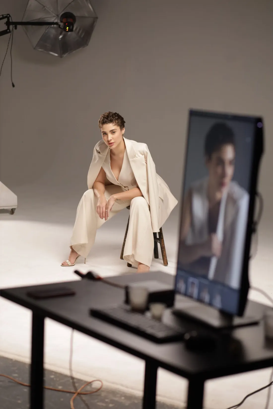 Mannequin en costume clair assise dans un studio blanc