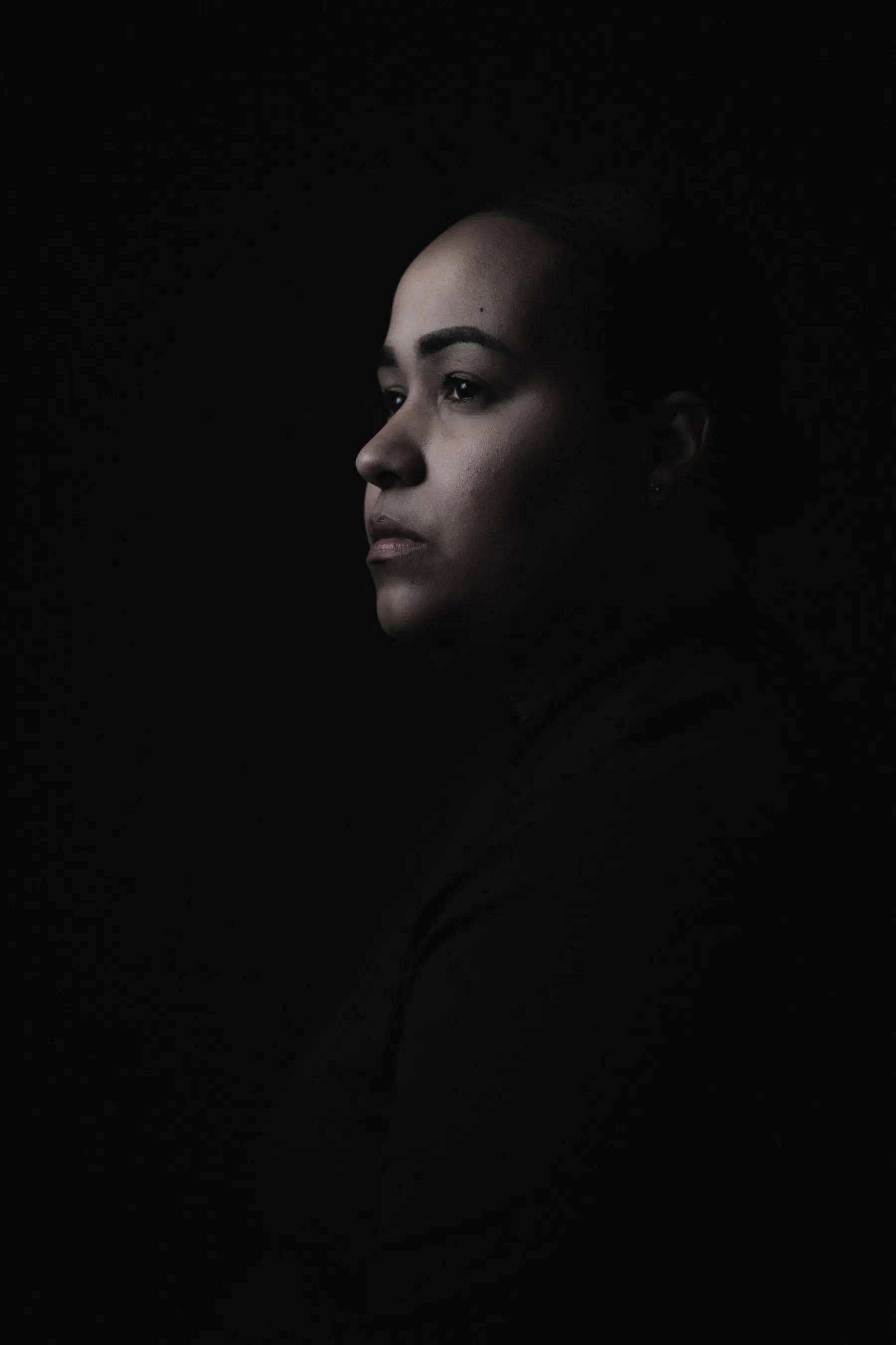 Portrait de profil en clair-obscur, visage éclairé sur fond noir