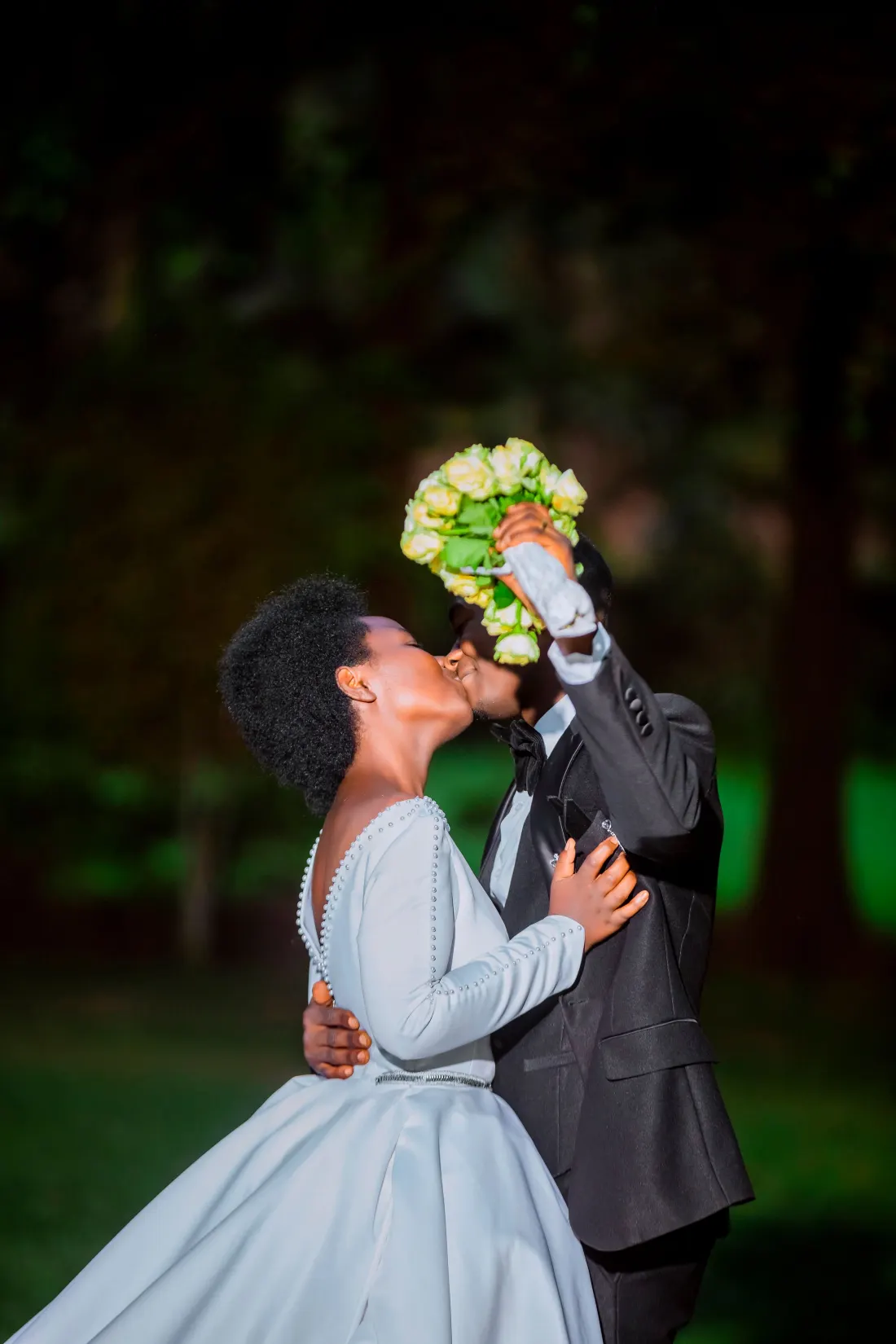 Couple qui s’embrasse derrière un bouquet de mariée