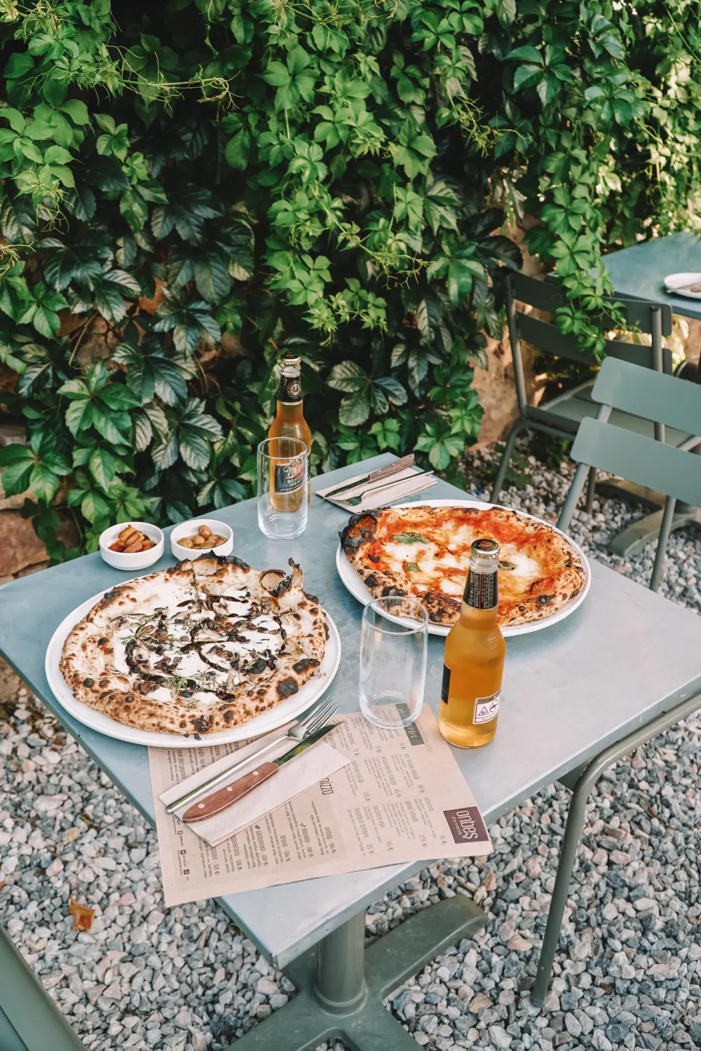 Table en terrasse avec pizzas et boissons fraîches