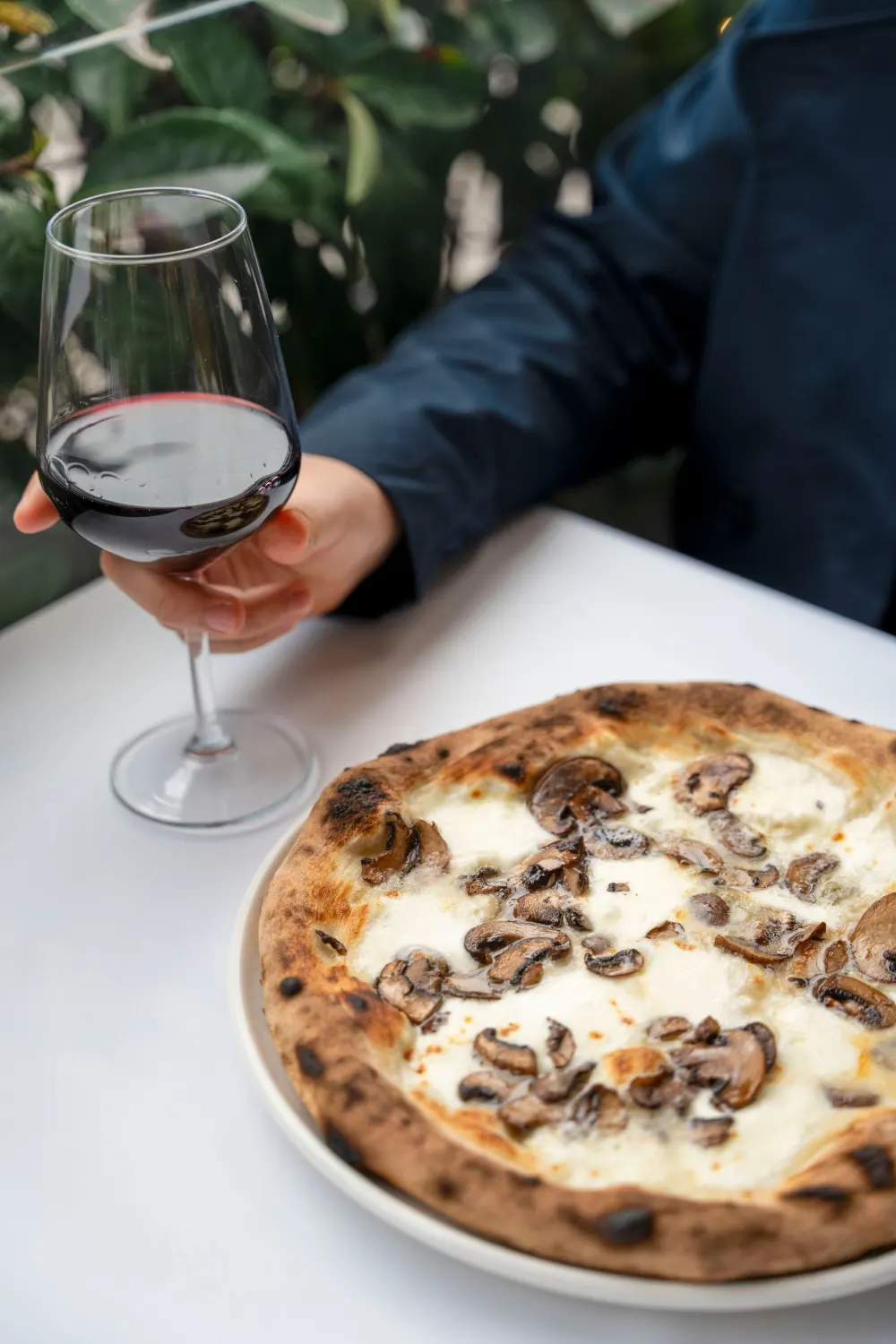 Verre de vin rouge posé à côté d’une pizza