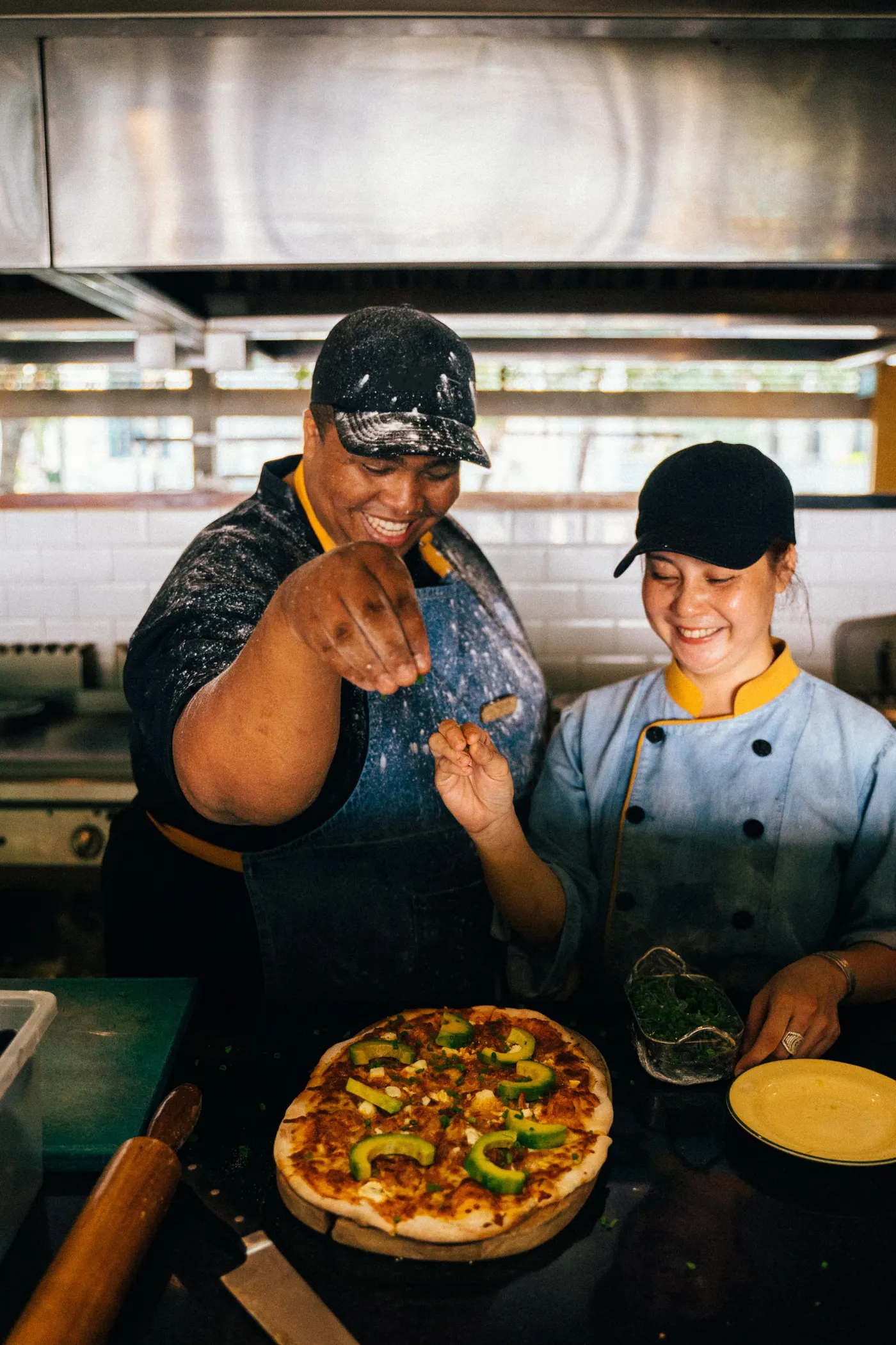 Deux cuisiniers qui préparent les pizzas en riant