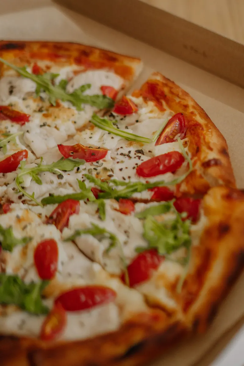 Pizza aux tomates cerises et roquette dans son carton