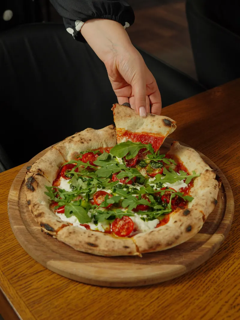 Main qui attrape une part de pizza à la roquette