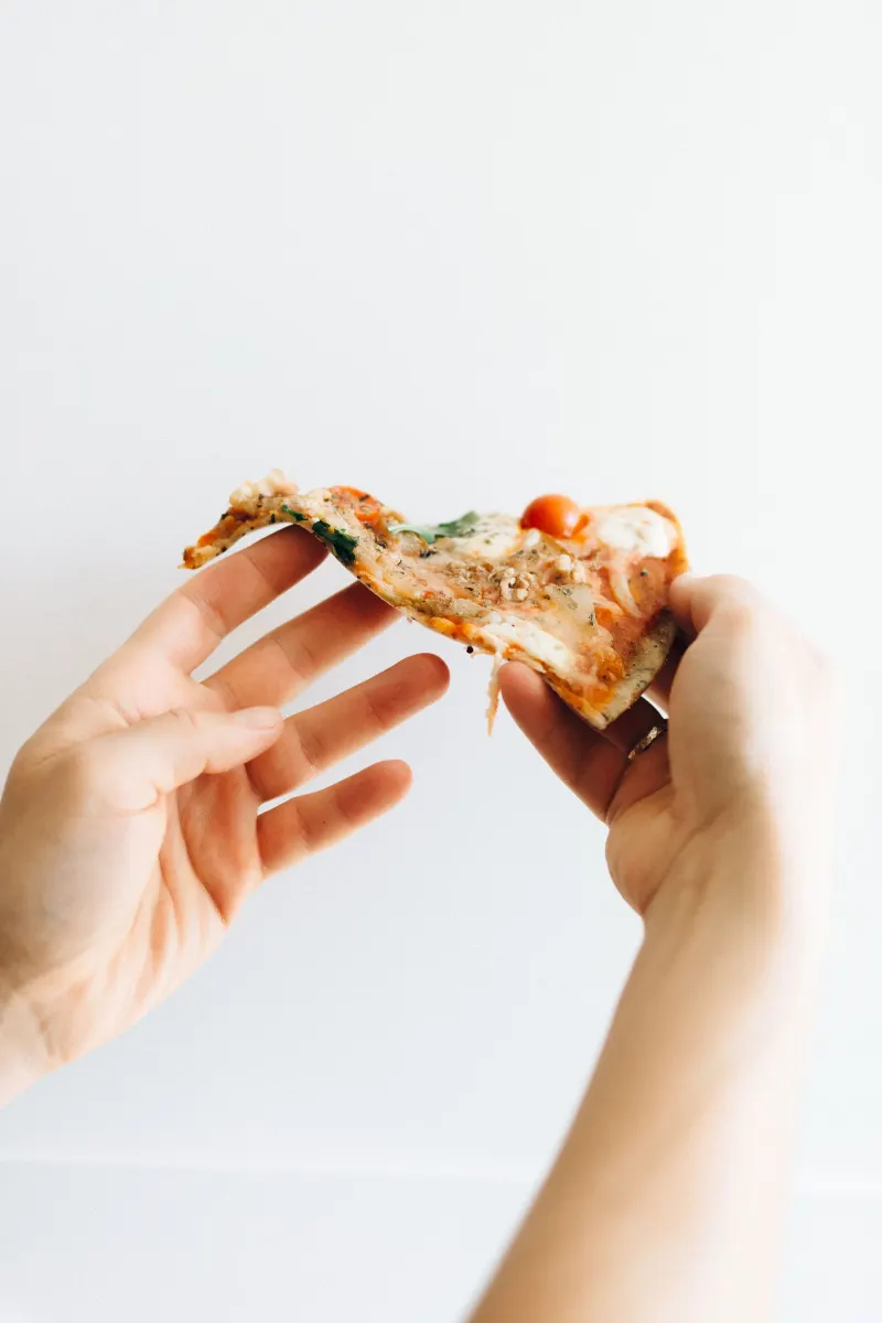 Part de pizza tenue à deux mains