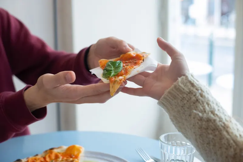 Amis qui partagent des parts de pizza autour d’une table