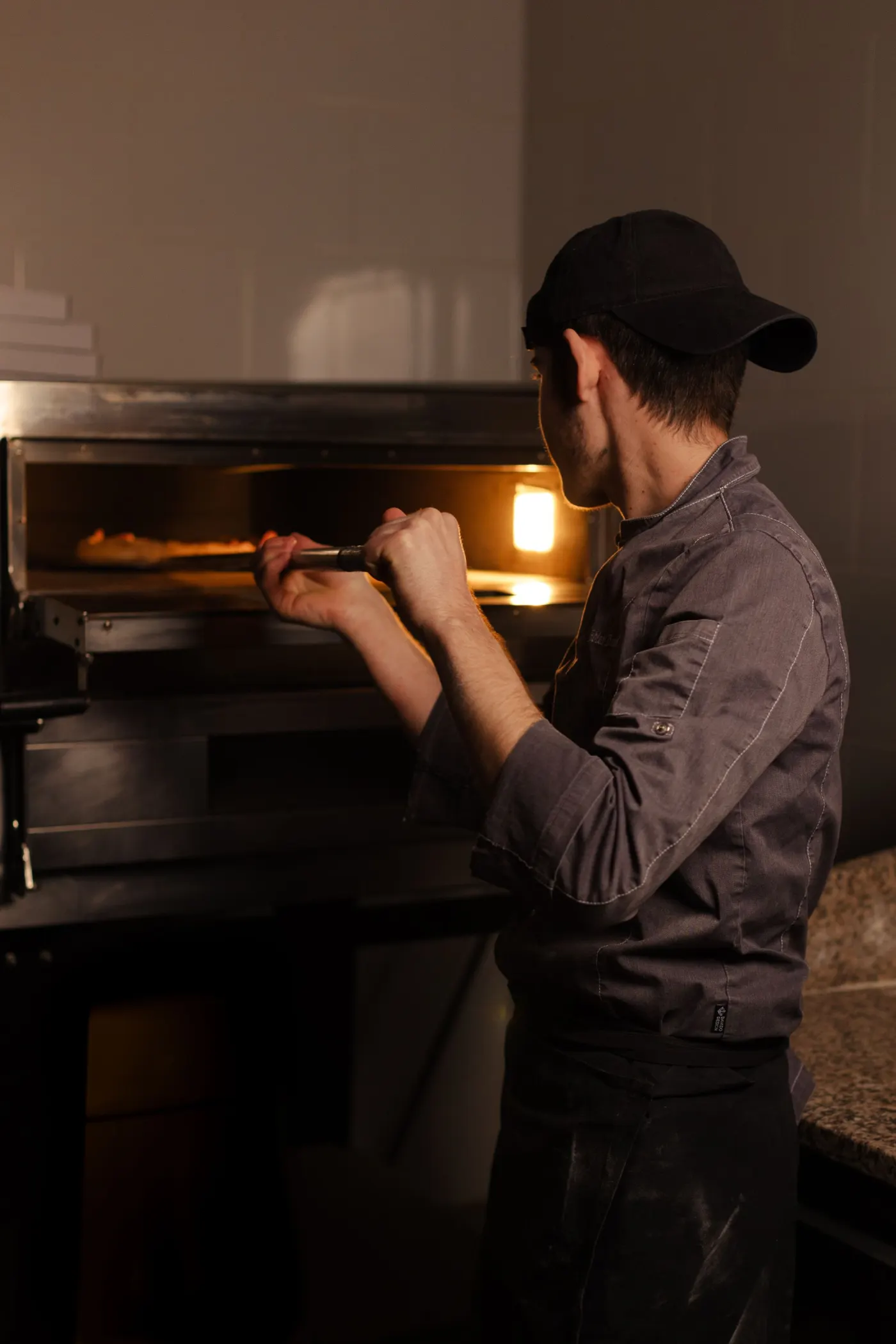 Pizzaiolo devant le four dans une lumière chaude