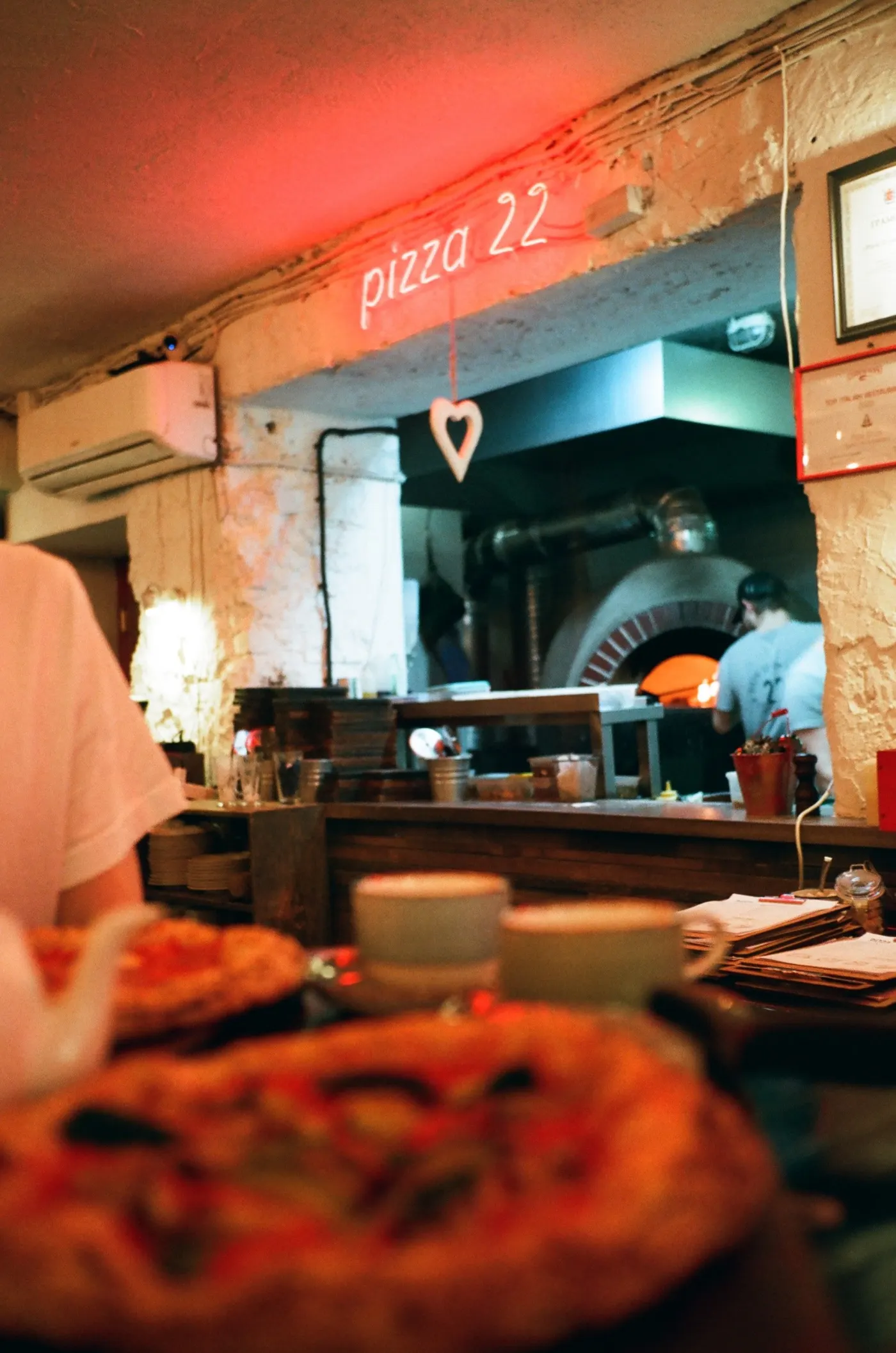 Salle chaleureuse de la pizzeria avec le four visible au fond