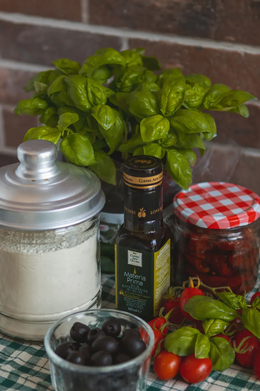 Basilic frais, farine et olives sur un plan de travail