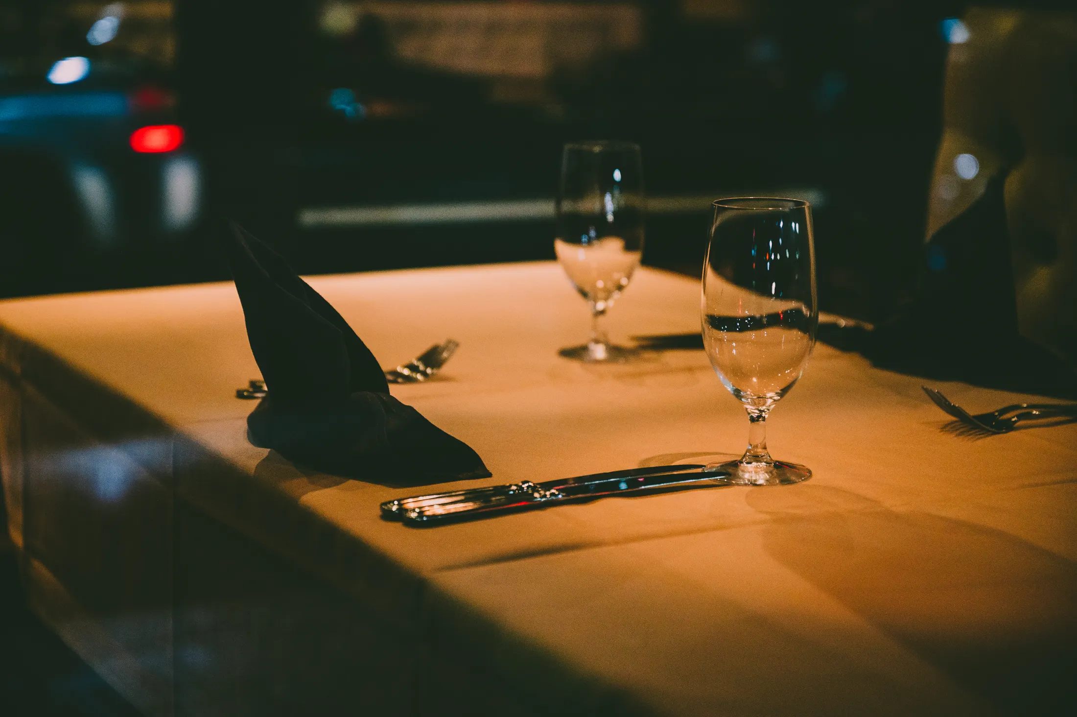 Une table dressée dans la salle, verres et nappe sous la lumière du soir