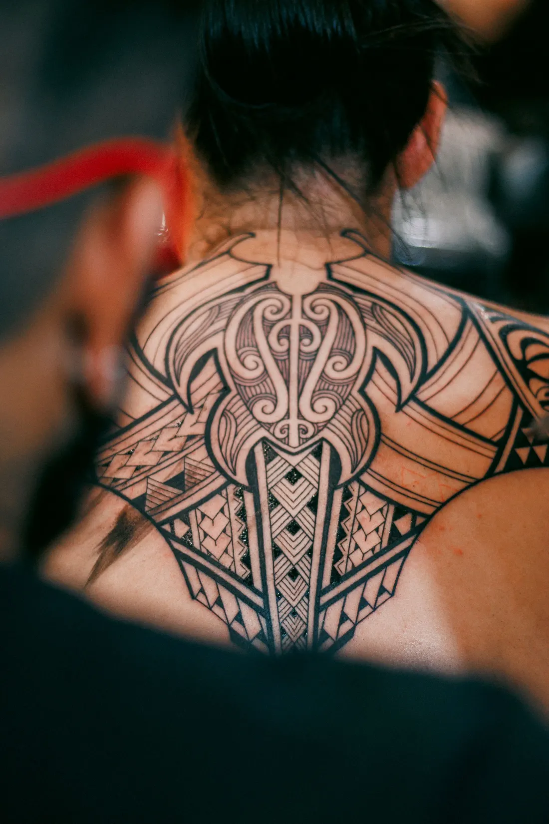 Grande pièce blackwork géométrique d’inspiration polynésienne sur la nuque et les épaules