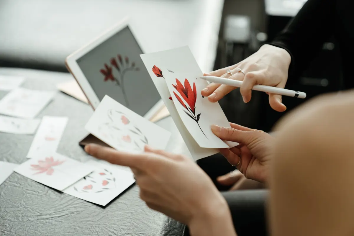 Deux personnes posent des croquis de fleurs rouges sur une table et en discutent