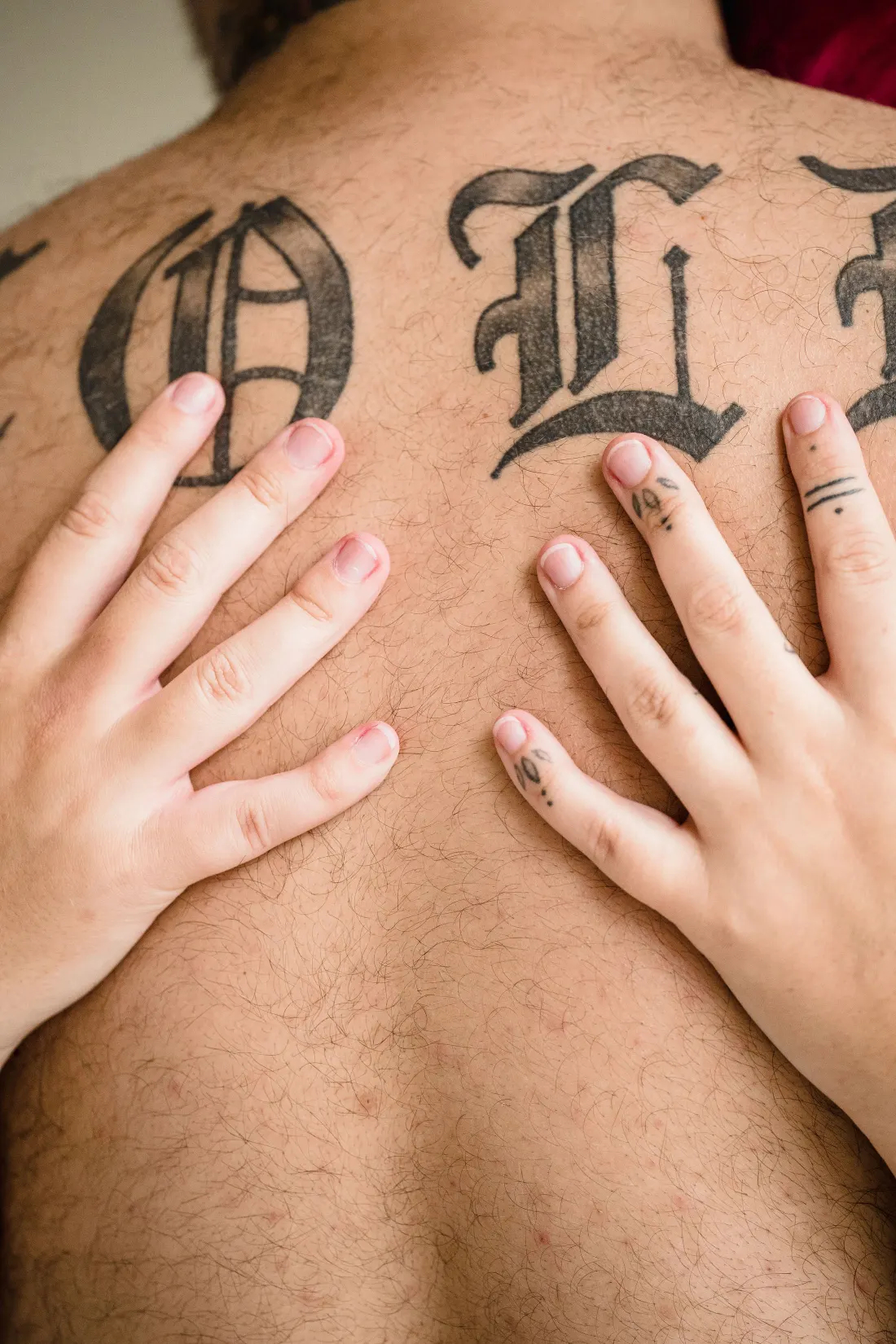 Grandes lettres gothiques noires en travers du haut du dos, deux mains posées dessus