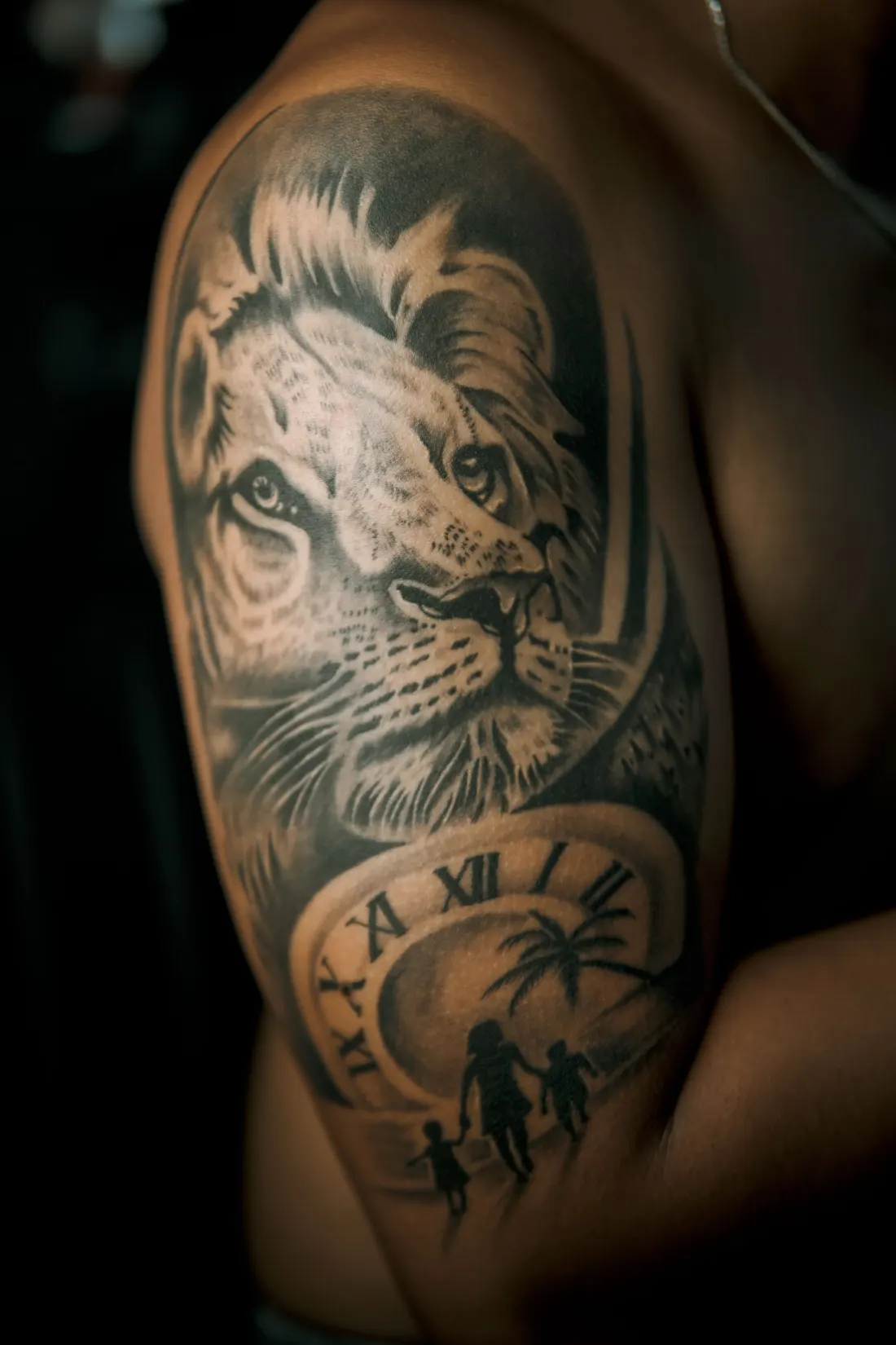 Tête de lion réaliste en noir et gris au-dessus d’une horloge, sur l’épaule
