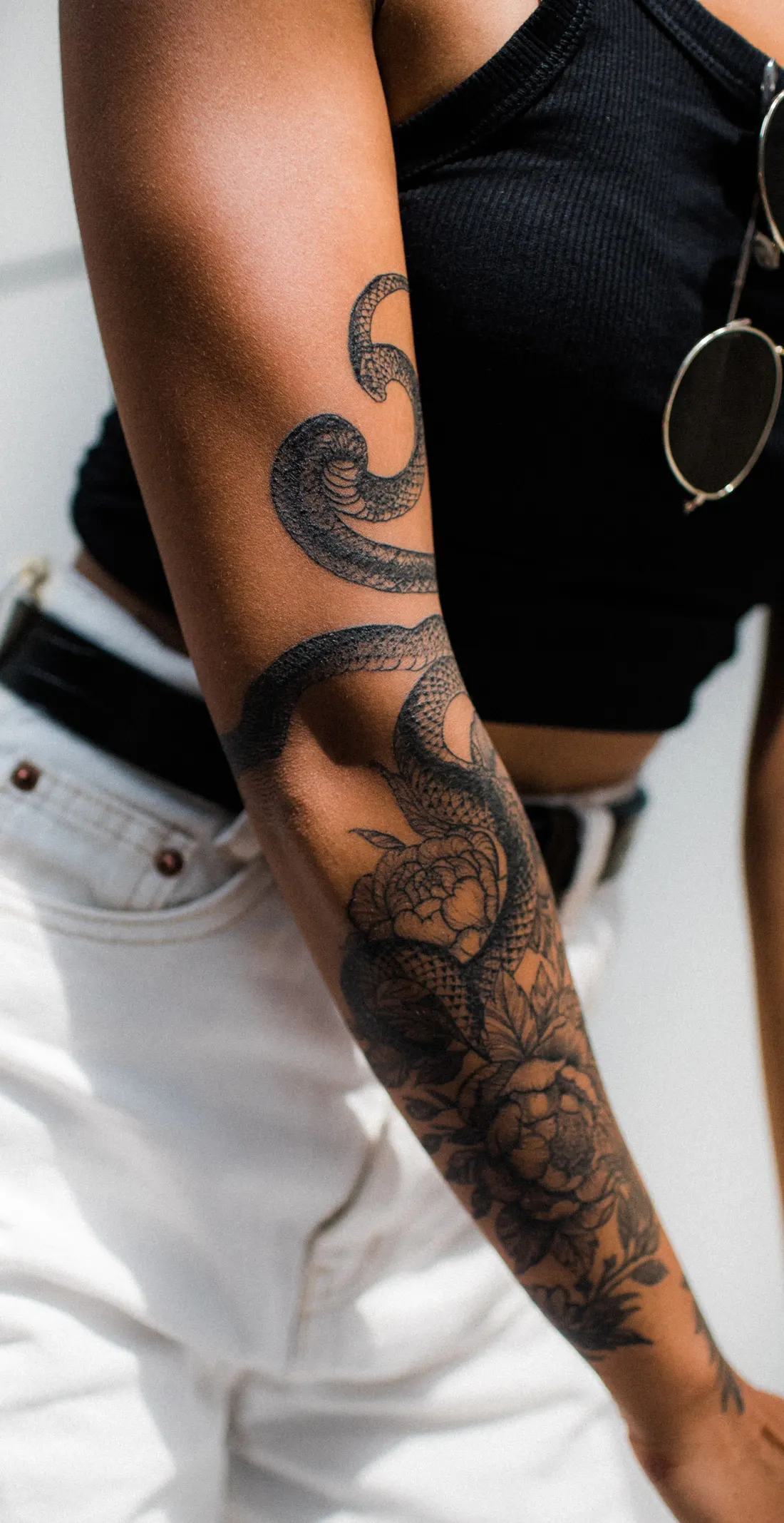 Bras de femme couvert d’un serpent enroulé autour de roses, en noir