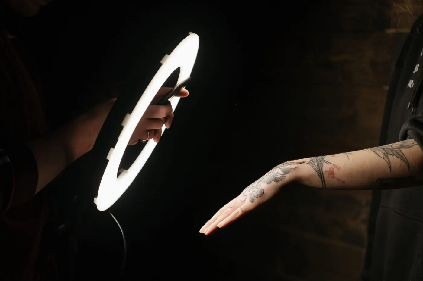 Anneau lumineux dans le noir éclairant un avant-bras tatoué