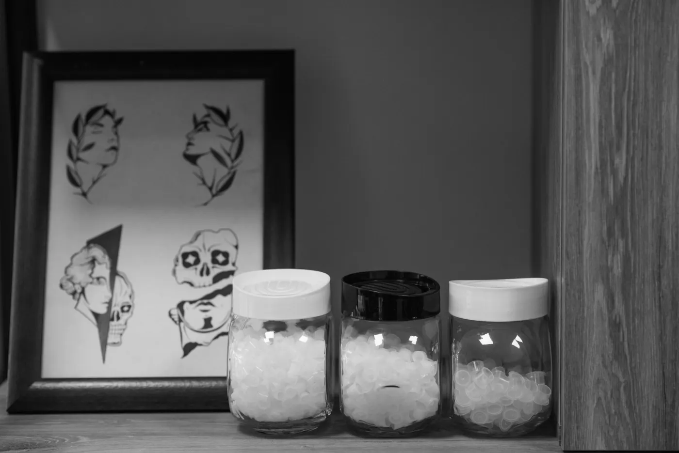 Bocaux de coton en verre devant des dessins encadrés