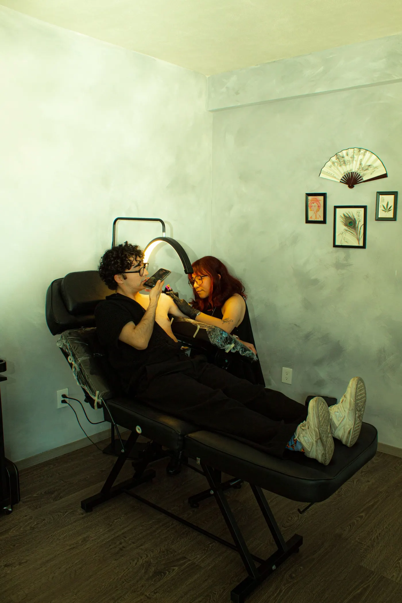 Fauteuil de tatouage noir incliné, mur vert pâle et petits cadres