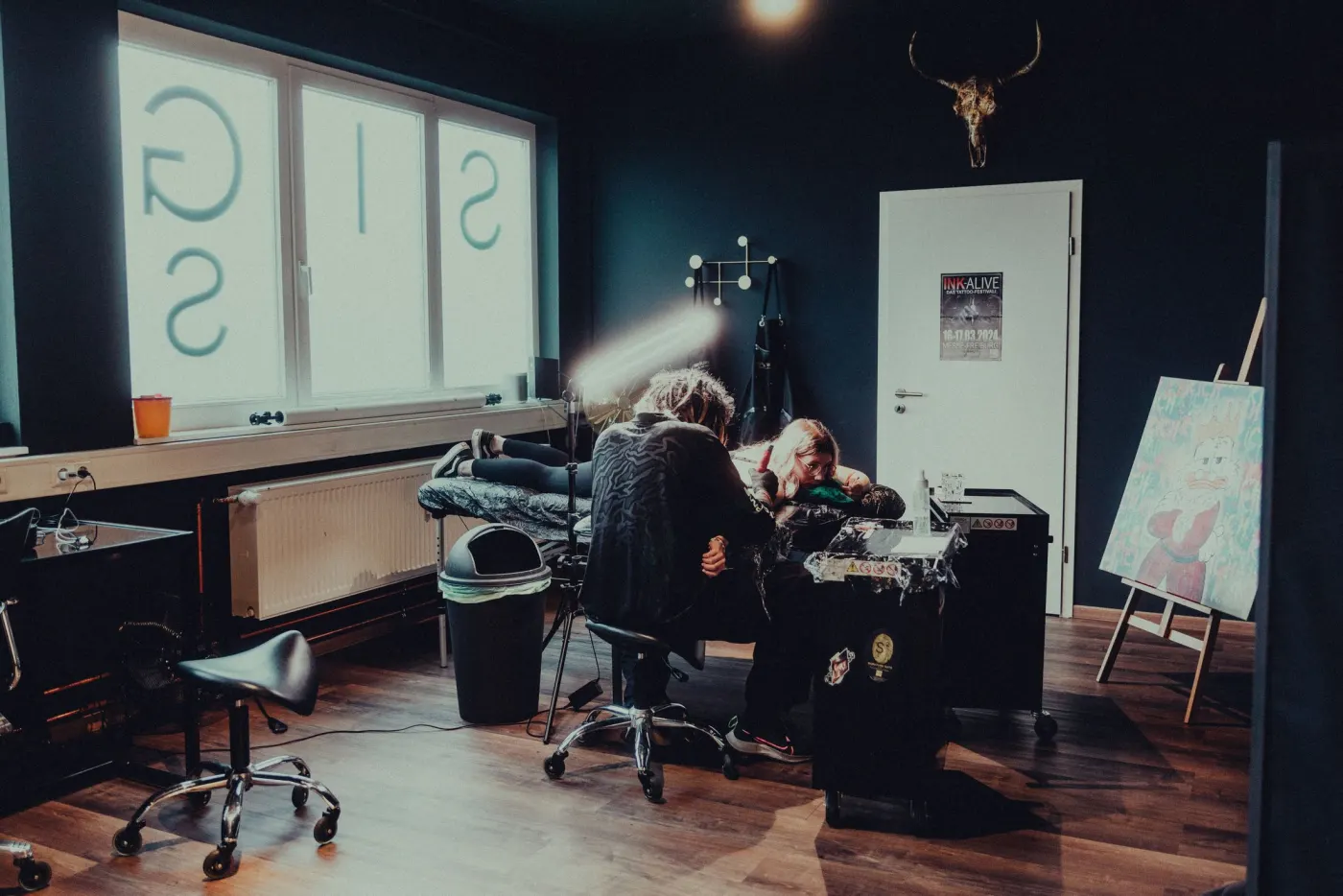 Studio avec grandes vitres, tatoueur au travail près du fauteuil