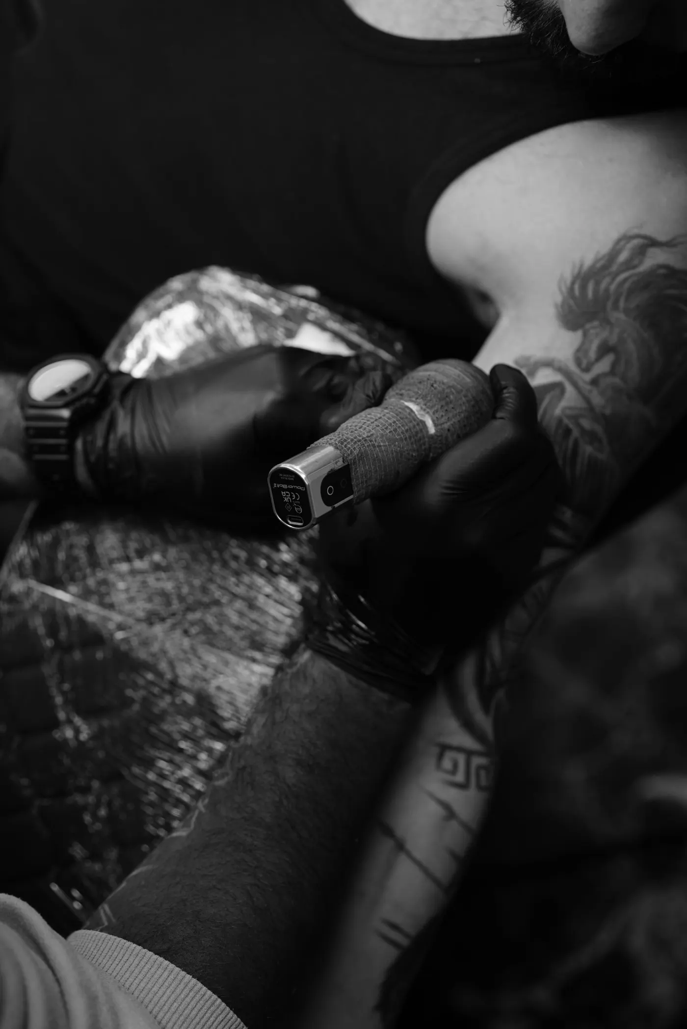 Machine stylo tenue par une main gantée au-dessus d’un avant-bras, noir et blanc