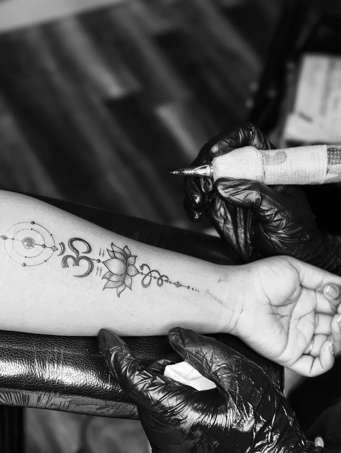Unalome et lotus en trait fin tatoués sur l’avant-bras, noir et blanc