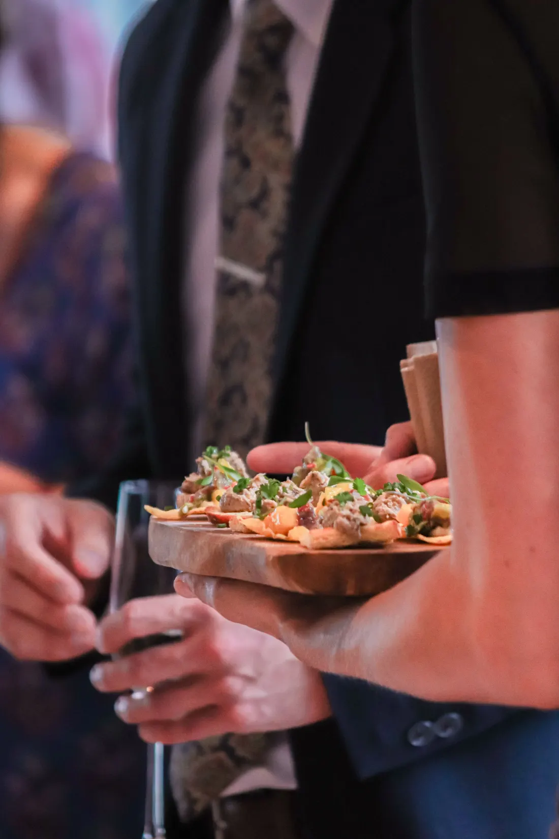Serveur qui présente un plateau de bouchées à des invités en soirée