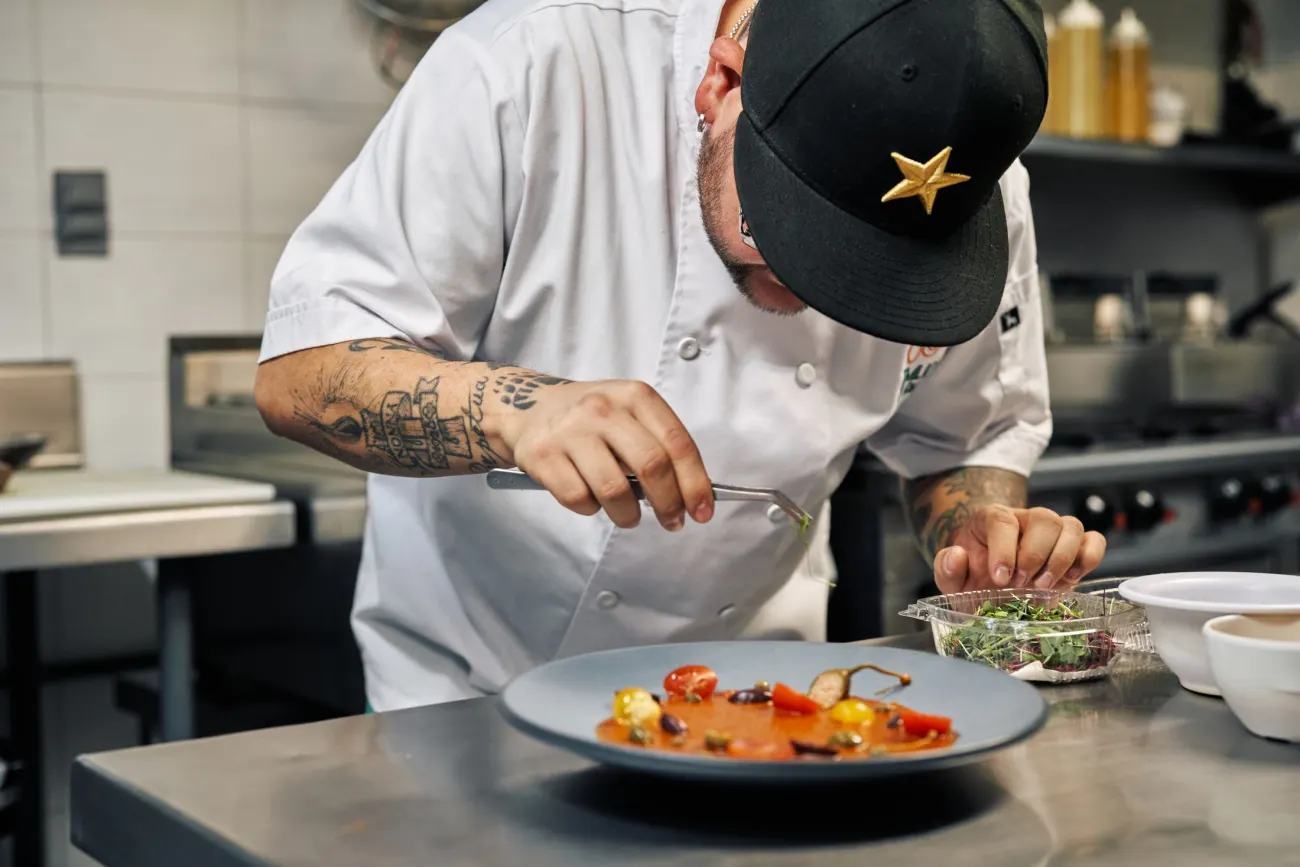 Chef qui dresse une assiette gastronomique à la pince