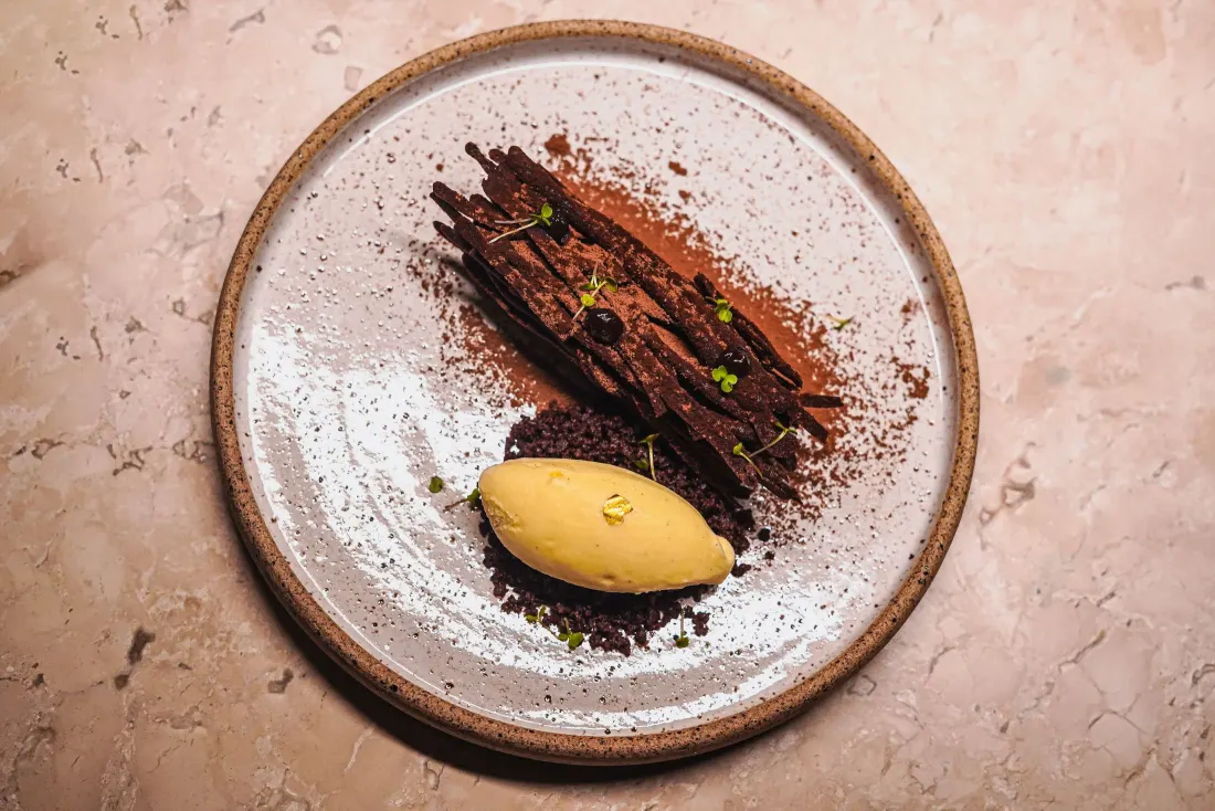 Dessert au chocolat avec quenelle glacée et éclats torréfiés