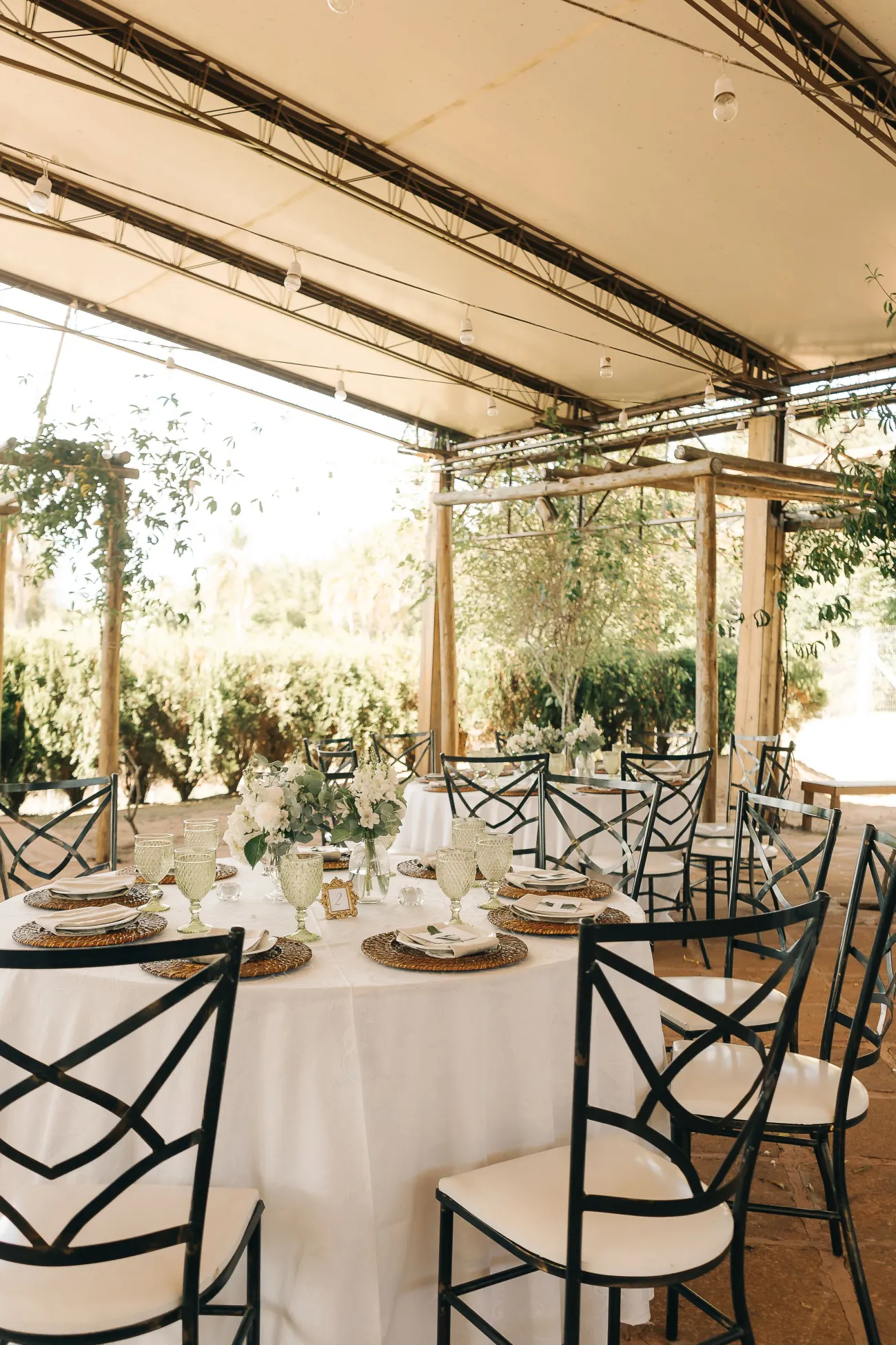 Réception de mariage sous une structure vitrée, tables rondes dressées en blanc